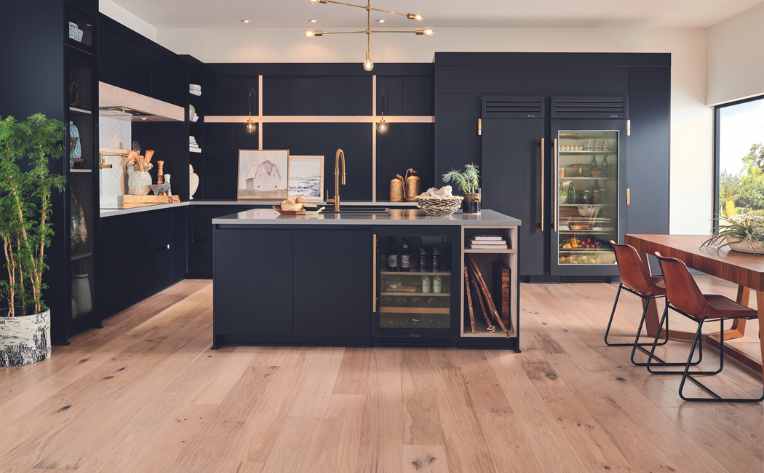 light hardwood floors in kitchen with navy blue cabinetry
