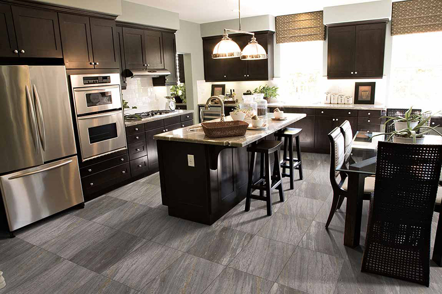 Kitchen with dark cabinets and grey luxury vinyl flooring that looks like stone