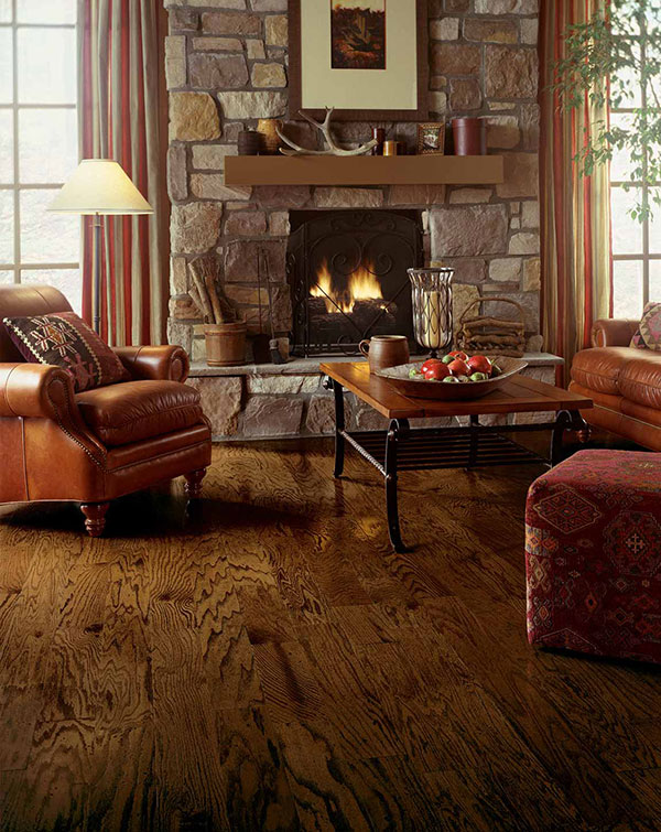 Family room with lit stone fireplace, hardwood floors, and overstuffed leather furniture that provides a woodsy theme.