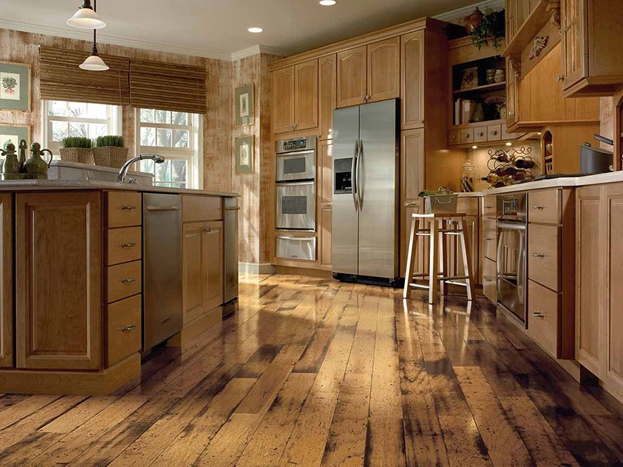 Kitchen with natural wood look floors, cabinetry, island and stainless steel appliances that create a rustic cabin theme.