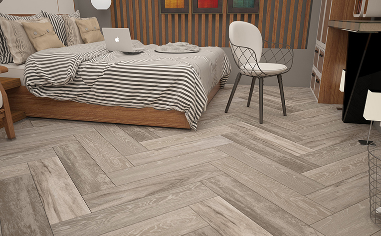 Distressed grey herringbone tile floors in a cozy bedroom.