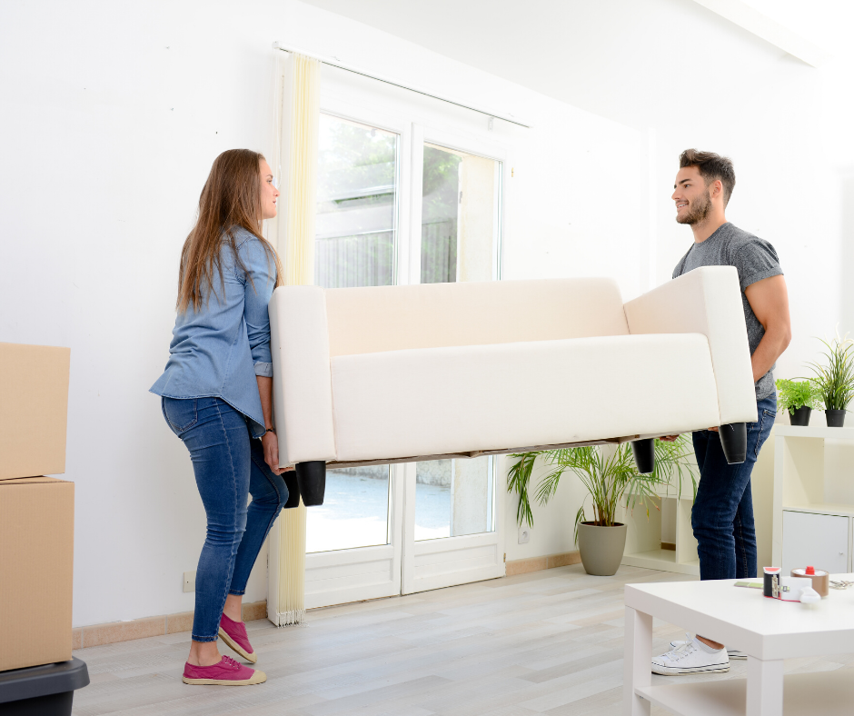 Man and woman carrying white couch out of room